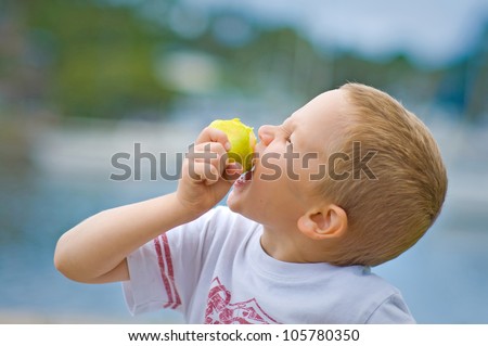 Young boy biting into fruit on a summer day