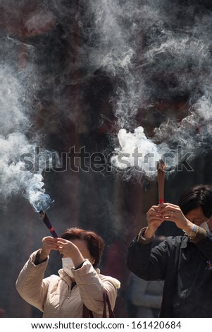 SHANGHAI, CHINA, APRIL 10: Unidentified group of people burning incense and praying in a temple in Shanghai, China 2013.