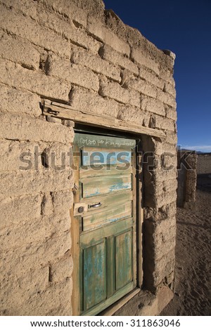 Old faded wooden colonial door and adobe architecture in a small village in Potosi State with morning light. Bolivia