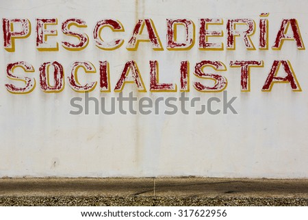 MARGARITA, VENEZUELA, APRIL 15: Painted old retro sign with the text Socialist Fish Market written in Spanih on a white grunge wall. Venezuela 2015