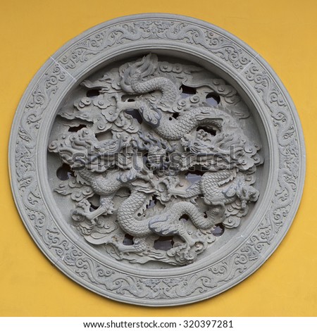 HANGHZOU, CHINA, APRIL 30: Ornamented window with dragon on a yellow wall of a temple in Hanghzou, China, 2013