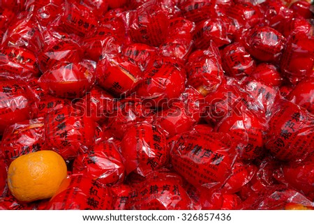 SHANGHAI, CHINA, APRIL 6: Single unpacked orange with other packed oranges in vibrant red plastic with chinese name of the brand in a market in Shanghai. China 2013
