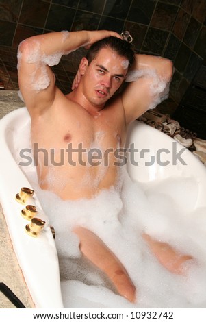 sexy muscular young man in a bubble bath spa with foam