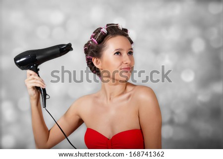 Girl dries hair at light background