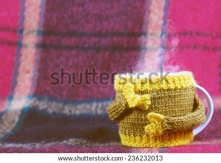 Knitted  yellow cup  at red rug background