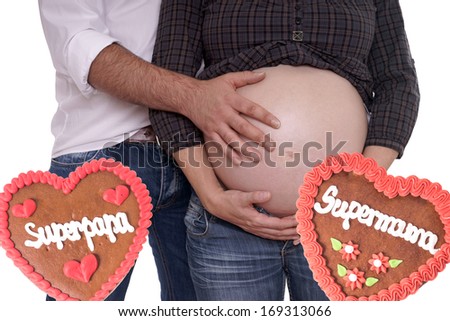 pregnant woman with her husband and gingerbread hearts with the german words super mom and super dad