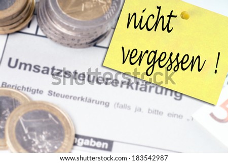 german VAT return with Euro coins and notepaper with the german words Do not forget / tax return