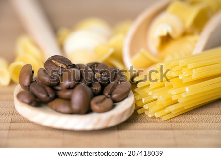 Wooden spoon with pasta and coffee beans on a wooden board / pasta with coffee beans