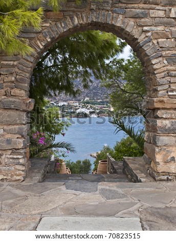 view of sea from garden stone walled arch Crete in Greece