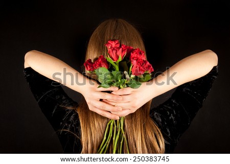 A young woman with a bouquet of roses on a black background