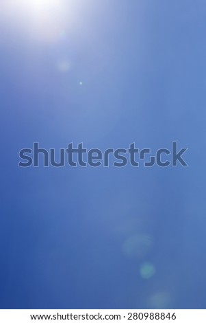 Light leak and a lens flare from the sun over clear blue sky with copy space