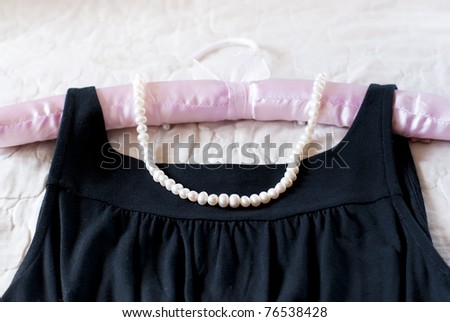 Black dress and pearl necklace on the clothes rack