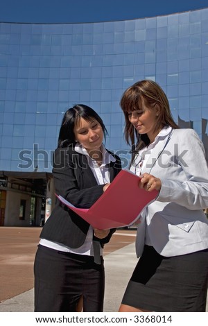 Women reading together a file of businesses of red color