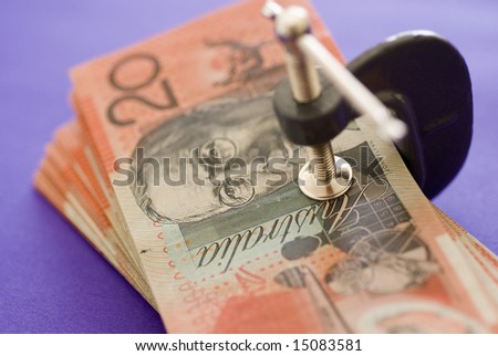 a wad of australian 20 dollar notes pressed in a G clamp