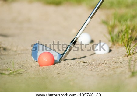 red golf ball in bunker