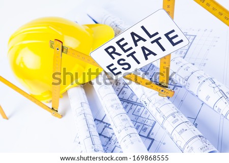isolated hard hat with blueprints and rulers on white and real estate sign