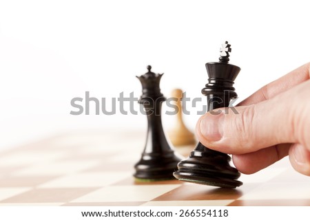 Hand putting a black chess king on a table
