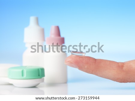 contact lens on finger and eye drops