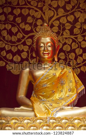 Gold Buddha figure set in front of a red and gold decorative background Thailand