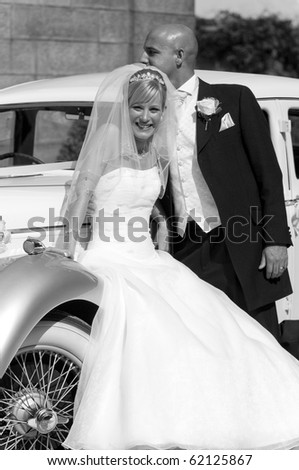 A stunning looking bride and groom next to a vintage wedding car