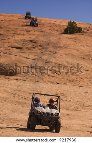 3 side-by-side ATVs coming down the side of a rock decline.