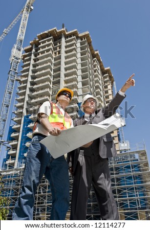 Developer and construction foreman looking over blueprints of a hirise construction project
