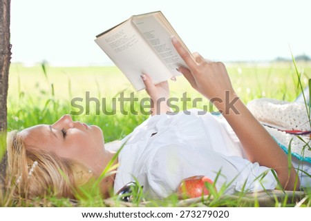 Young girl outside lie in park reading book, enjoy nice sunny day