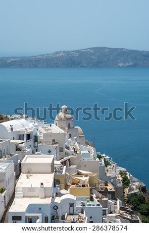 Small greek church building in Fira, Santorini, with a view of the caldera in the distance