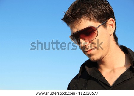Fashion man portrait in sunglasses over blue sky