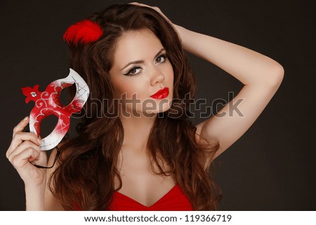 Beautiful Woman with red lips holding Carnival mask in hand.