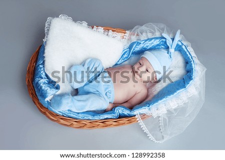 Adorable baby boy wearing in blue clothes resting in basket