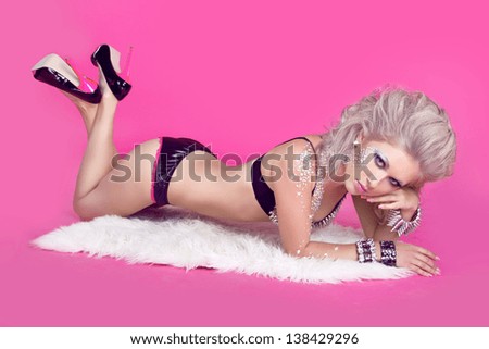 Beautiful woman with hair styling lying over pink background. Sexy girl in lingerie. Fashion art photo