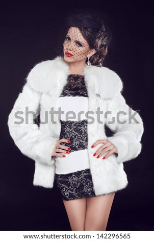 Fashion model woman wearing in luxury fur coat and elegant dress. Isolated on black background. Retro girl.