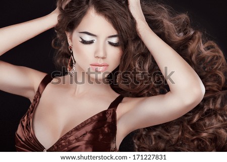 Long wavy hair. Beautiful woman portrait with curly brown hair isolated on black background