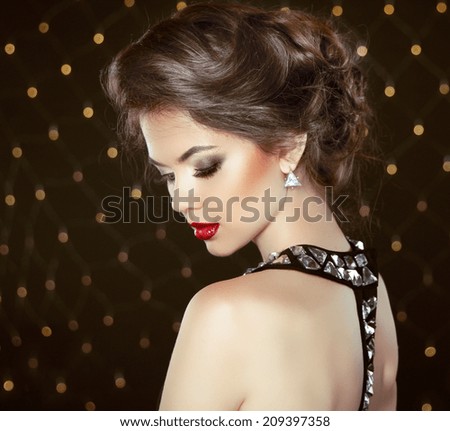 Fashion Brunette Model Portrait. Jewelry and Hairstyle. Elegant lady over bokeh lights background