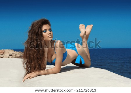 Attractive girl  in bikini on a yacht at summer day. Bronzed skin. Long wavy hair. Wellness. Makeup.