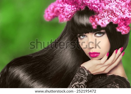 Attractive Brunette Girl with Flowers Long Hair. Healthy Black Hairstyle. Makeup. Manicured nails. Beauty Model Woman isolated on green natural background.