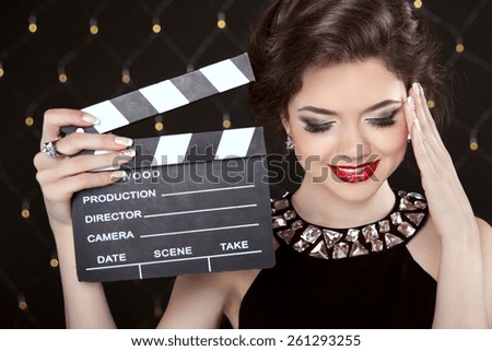 Fashion elegant woman posing with sexy red lips holding cinema clap. Super star model shot. Happy smiling girl.