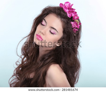 Beauty Brunette Girl Portrait with eye Makeup and flowers in long wavy hair. Enjoying. Spring freshness.