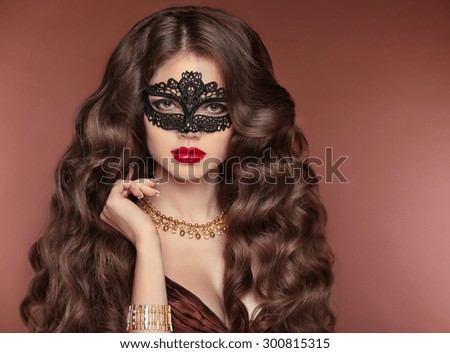Wavy Hair. Beautiful Brunette Girl. Makeup. Red Lips. Fashion lady wearing venetian masquerade carnival mask. Jewelry. Beauty Model Woman. Healthy Long Curly Hairstyle.