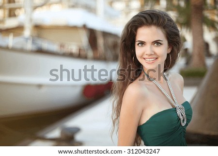 Beautiful teen girl smiling against the boat at sunset, outdoor portrait. Porto Montenegro.