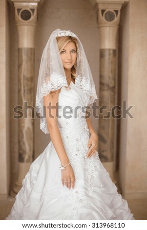 Beautiful smiling bride woman in wedding dress and bridal veil posing in interior. Beauty indoor portrait.