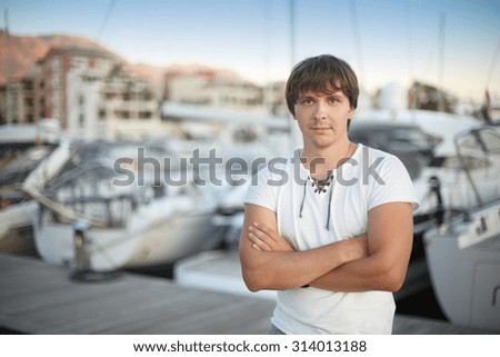 Smart Handsome man by luxury yacht background on the beach at sunset. Outdoor portrait. Porto Montenegro.
