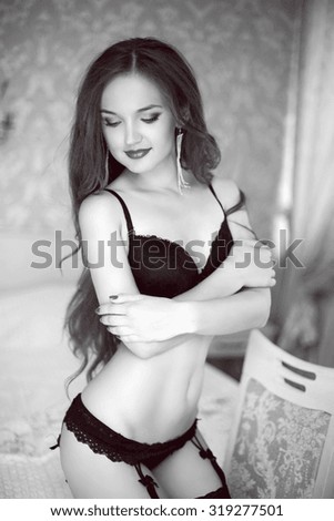 Beautiful cute smiling girl in sexy black lingerie in modern interior apartment. Black and white portrait.