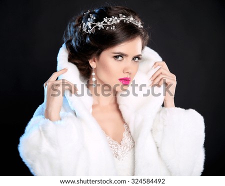 Hairstyle. Jewelry. Beautiful fashion girl model winter portrait. Woman in luxury fur coat isolated on dark background.
