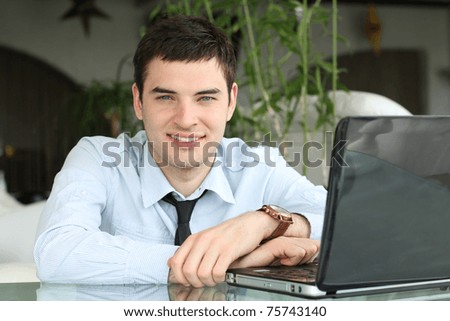 businessman at table with laptop in office. Smile. White teeth