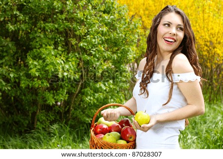Happy Female in white dress presents basket of apples