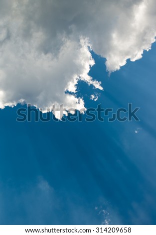 Suns rays beaming from behind clouds in sky