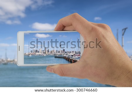 Tourist hand holding smart phone, taking photo of Auckland New Zealand, Harbor bay Bridge