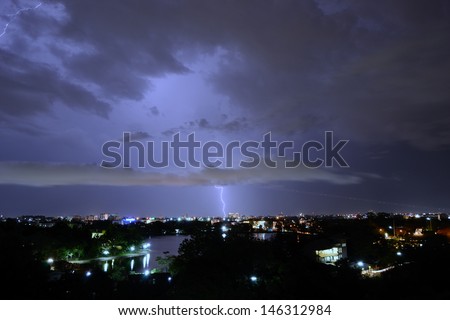 The real lightening over the city and the airplane take off at night time